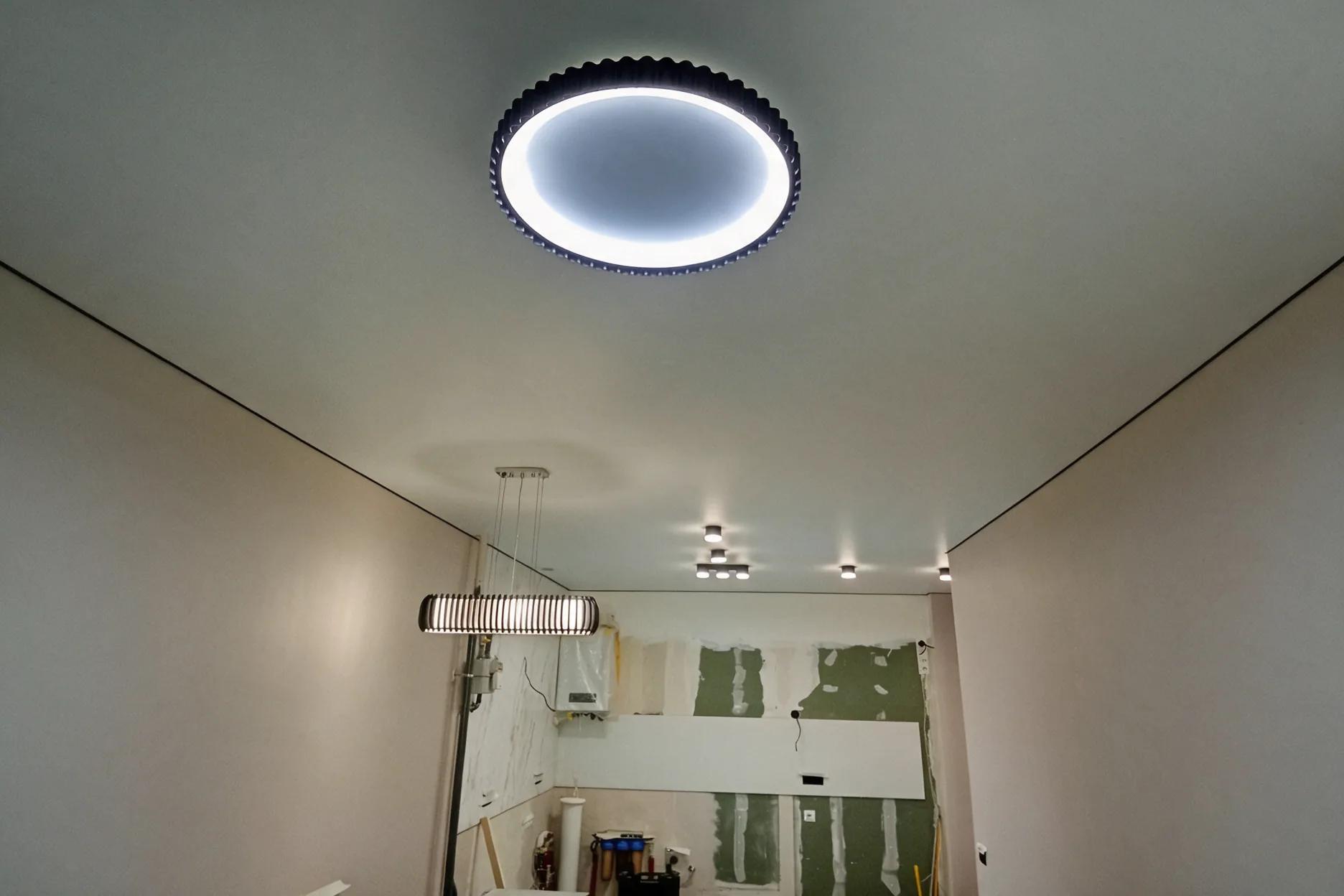 Кухонна зона: круглий LED-світильник, лінійна люстра і споти